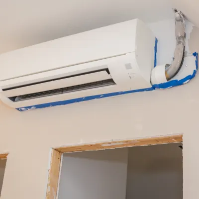 A newly installed wall-mounted air conditioner with painter’s tape still on the wall trim
