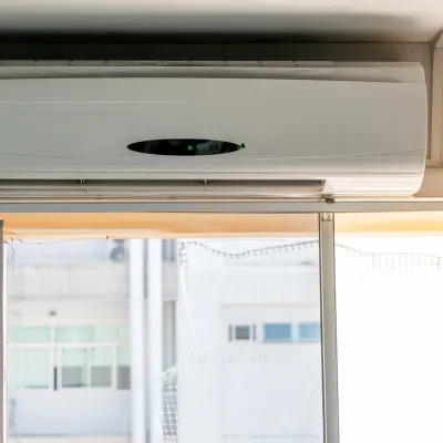 A wall-mounted air conditioner above a large window